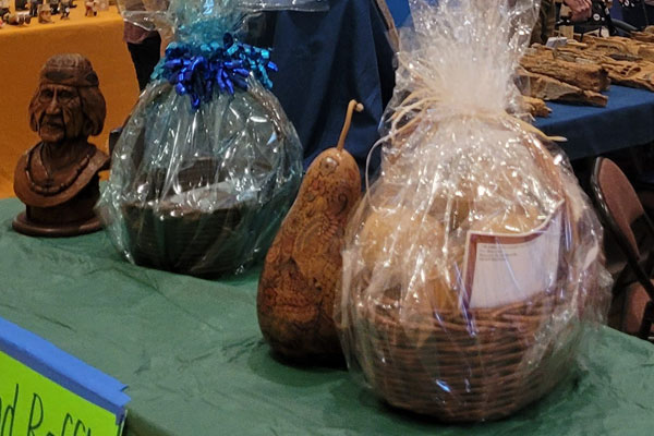 Raffle prizes from left Nelson Krouse's carved bust of a native woman, CWA Gift Basket, ,Janice Horner's gourd, Gourd society gift basket.